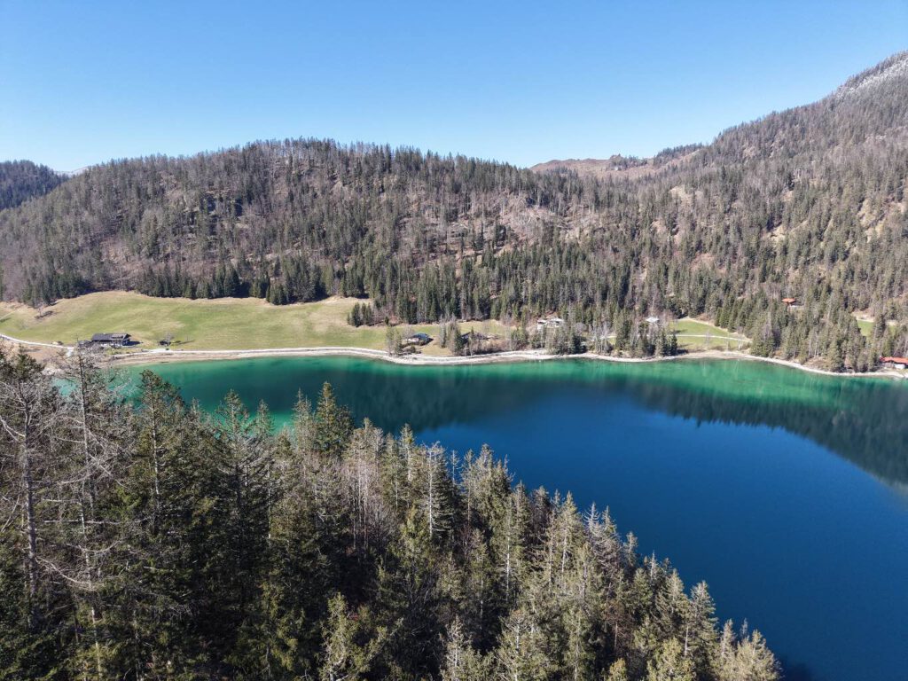 Hintersteiner See im Frühling, Luftaufnahme eines klaren Sees umgeben von Wäldern und Wiesen.