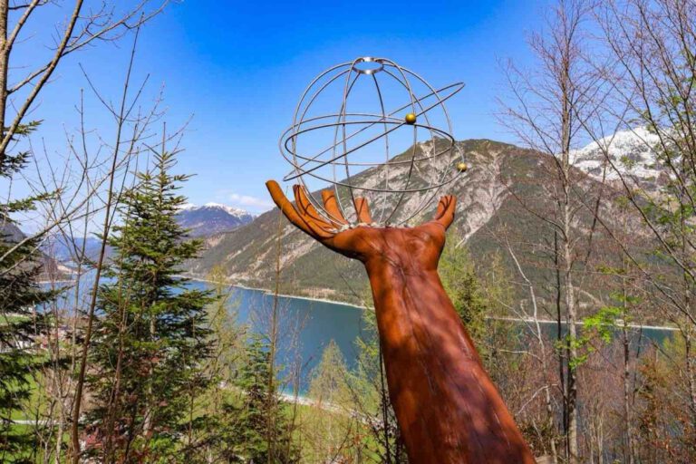 Skulptur Hand Gottes mit Kugel vor Bergpanorama am Besinnungsweg Achensee in Pertisau