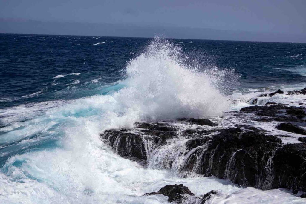 Wellen brechen an den schwarzen Lavafelsen der Küste von Güímar