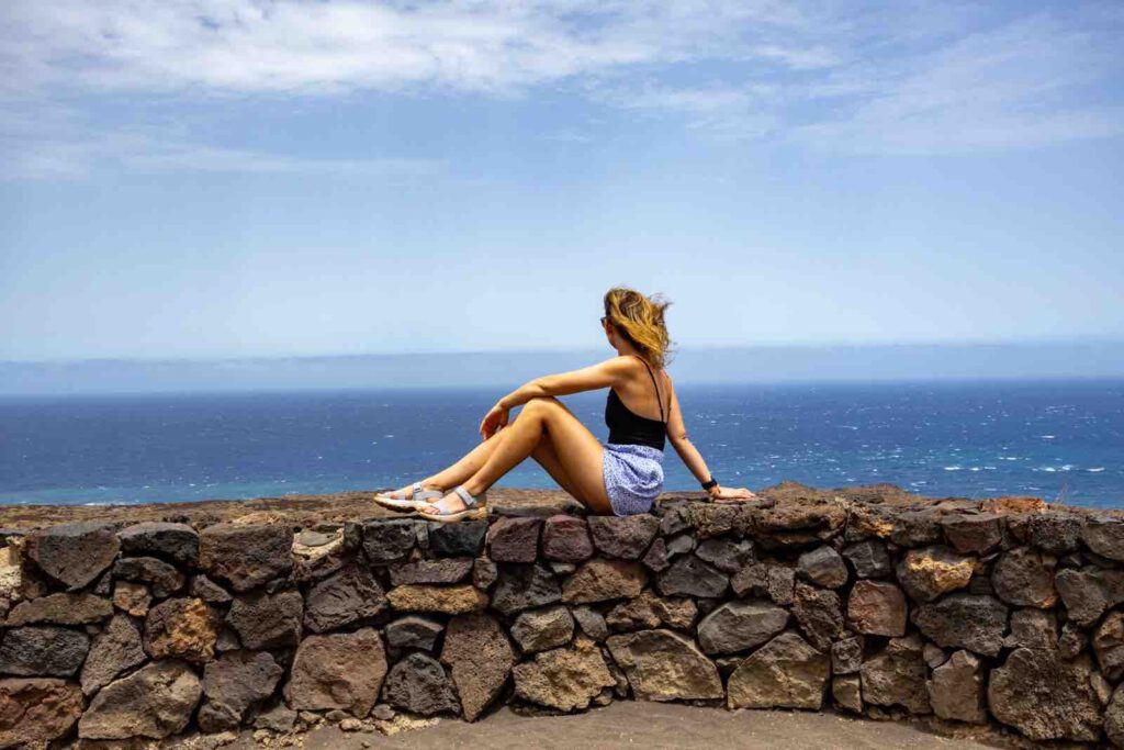 Wanderin Christin Großheim auf einer Lavasteinmauer an der Küste des Malpaís de Güímar