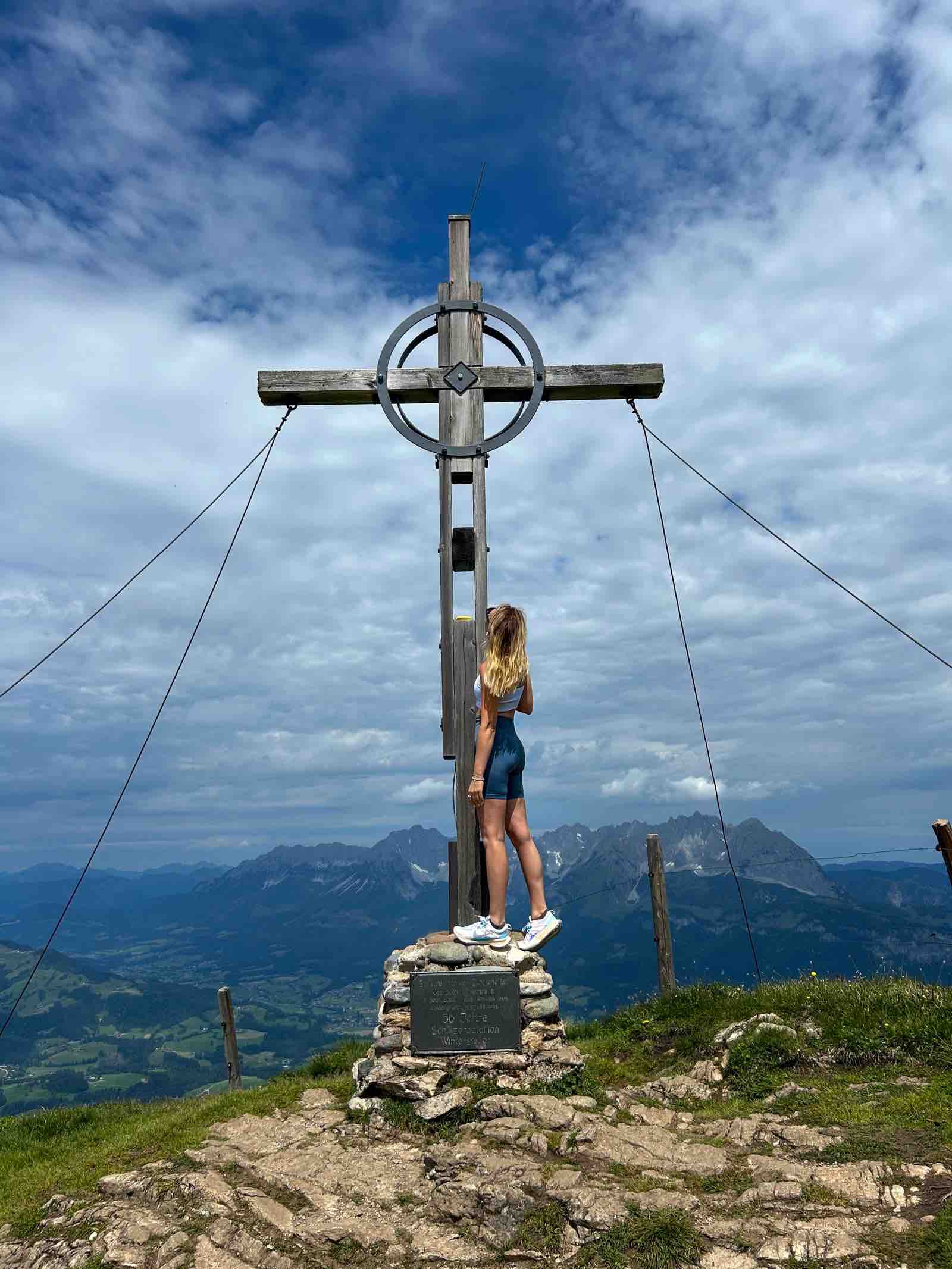 Wanderin Christin Großheim am Gipfelkreuz Kitzbüheler Horn mit Bergpanorama